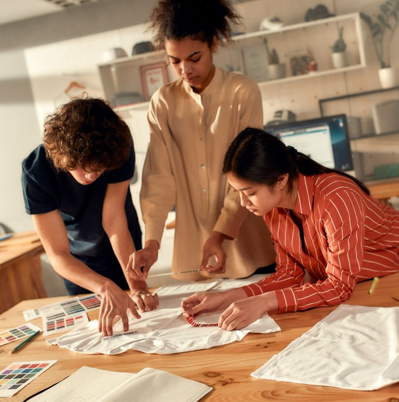 Photo capturing a 3 students working on a t-shirt design for a school fundraising event